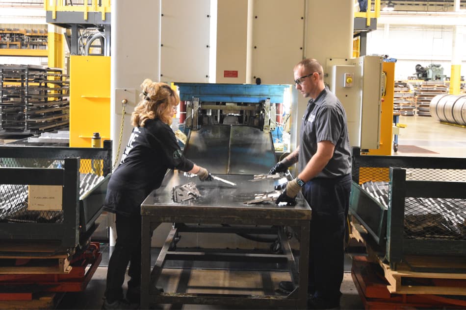 ATD employees working on auto parts using high-precision metal stamping press